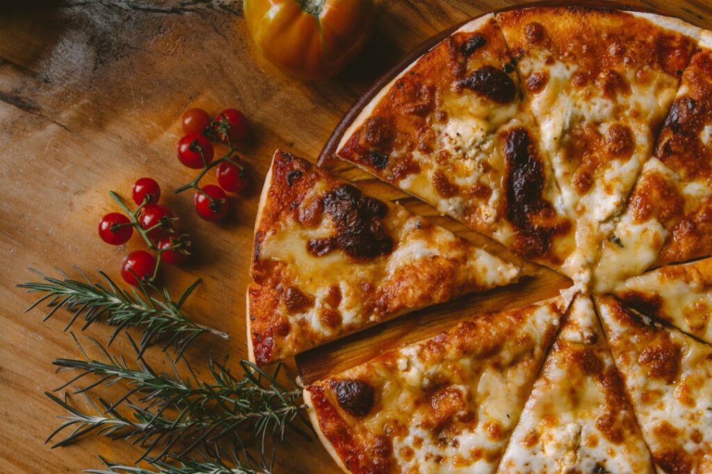 A close-up of freshly melted cheese stretching as a slice of pizza is lifted from a pie.