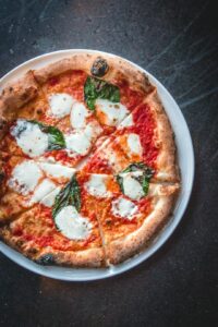 A shared table with several distinct pizza styles showing thin crust, pan crust, varied toppings, and browned edges.